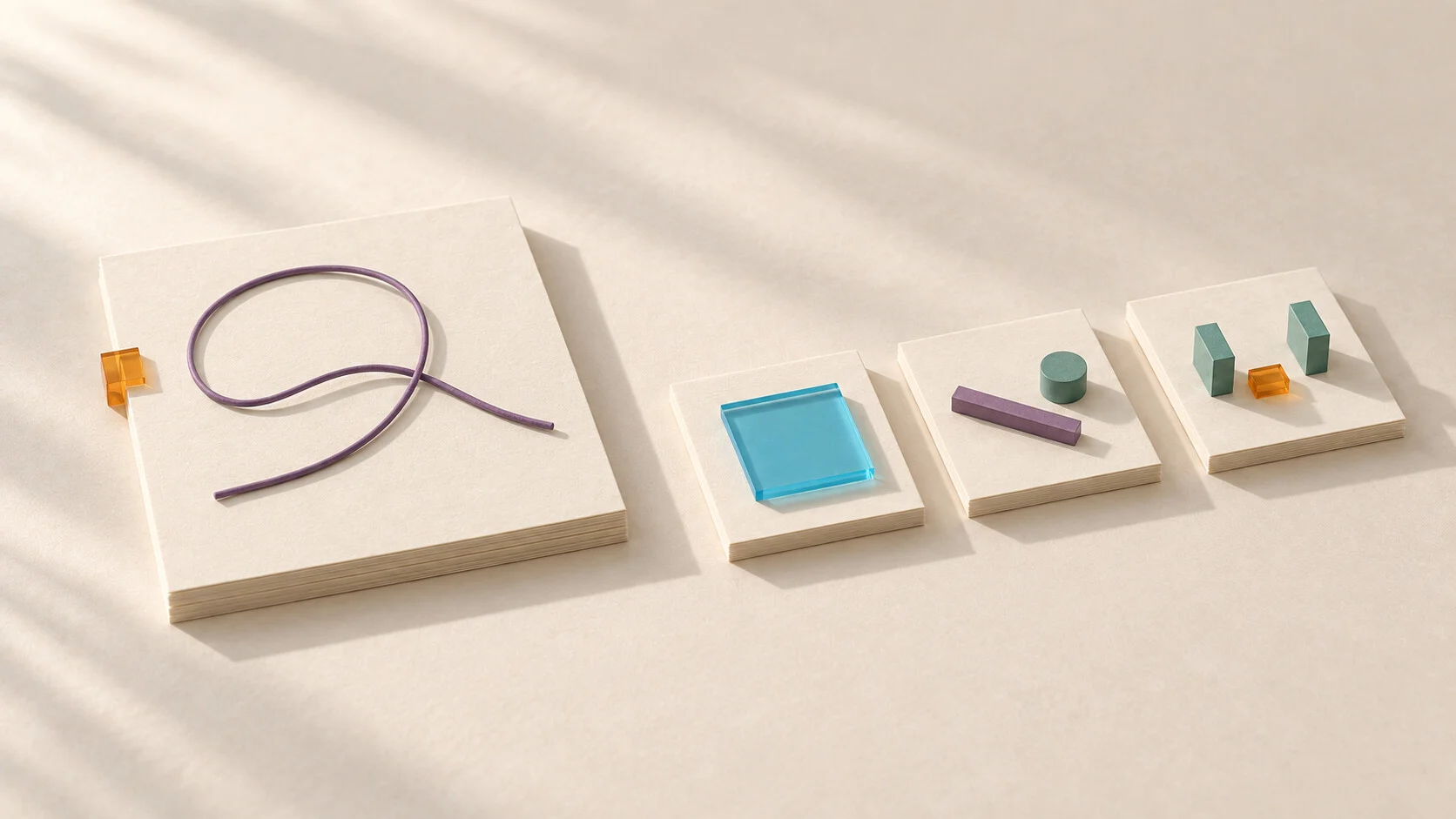 A loose purple cord rests on a large ivory sheet beside three smaller cards holding a cyan pane, separate control components, and teal supports with an amber spacer.