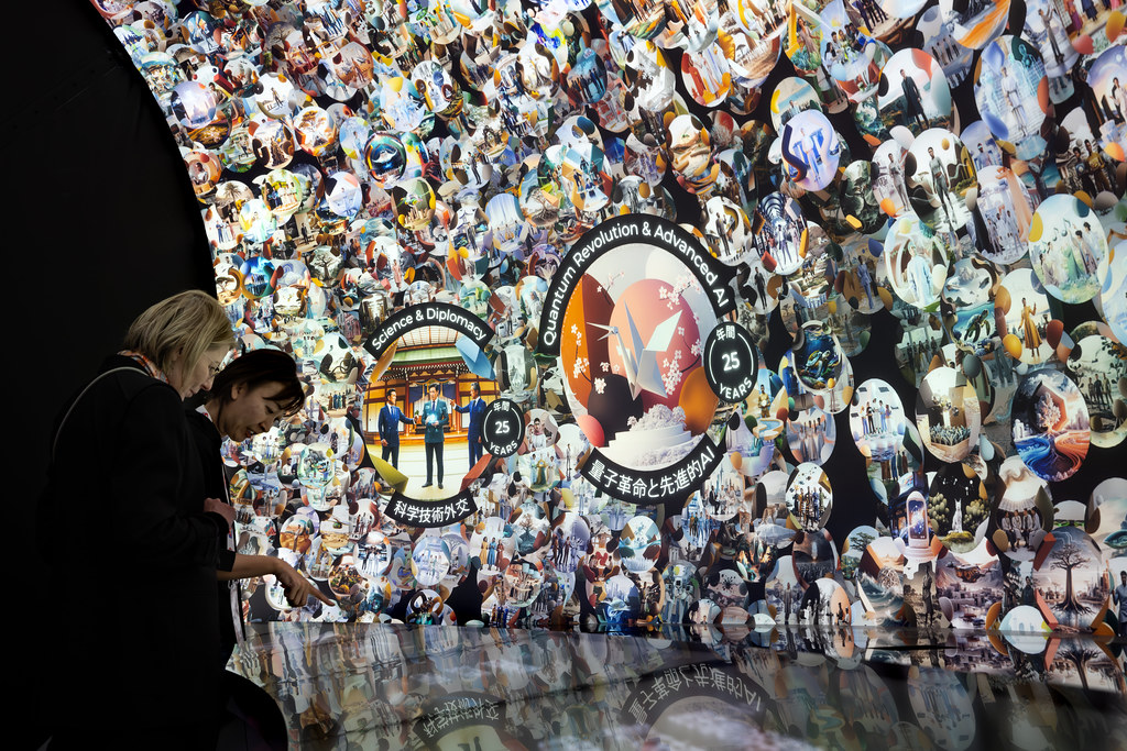 Two visitors reading visions on the projected wall, including Science and Diplomacy and Quantum Revolution and Advanced AI at the 25-year horizon.